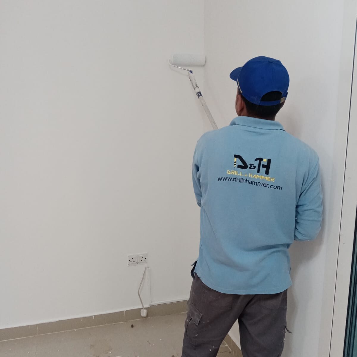 a professional expert is painting a wall by drill and hammer painting services in abu dhabi