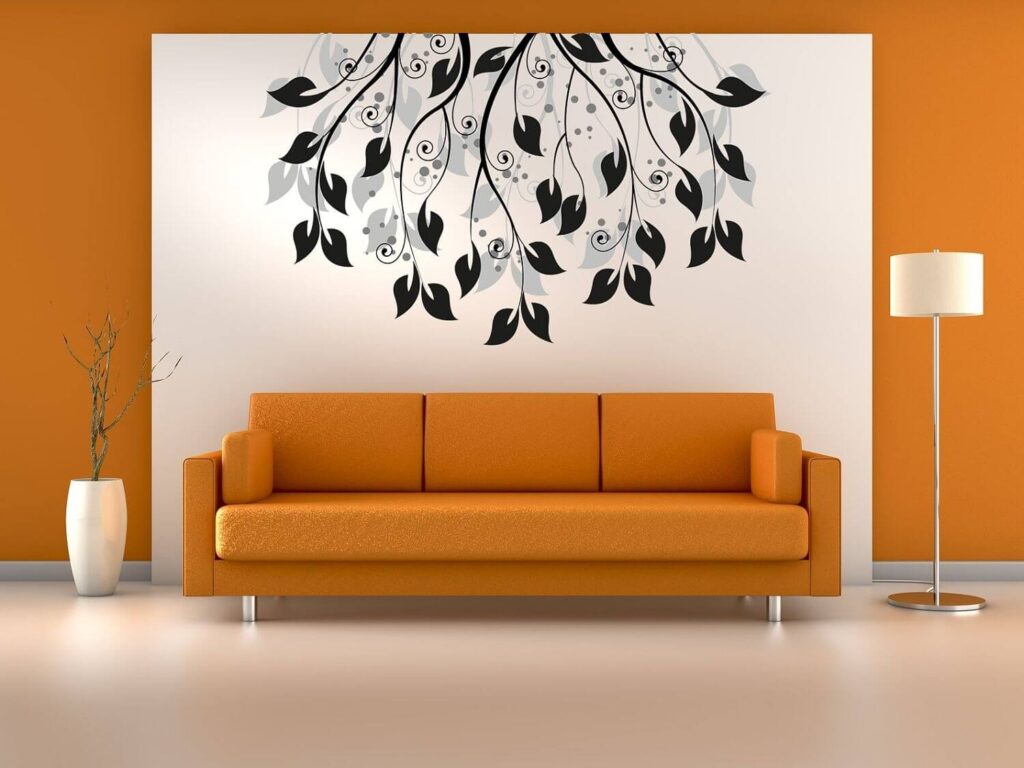 a sample of orange wall and a stenciled painted artwork on wall of living room. a creative wall painting design